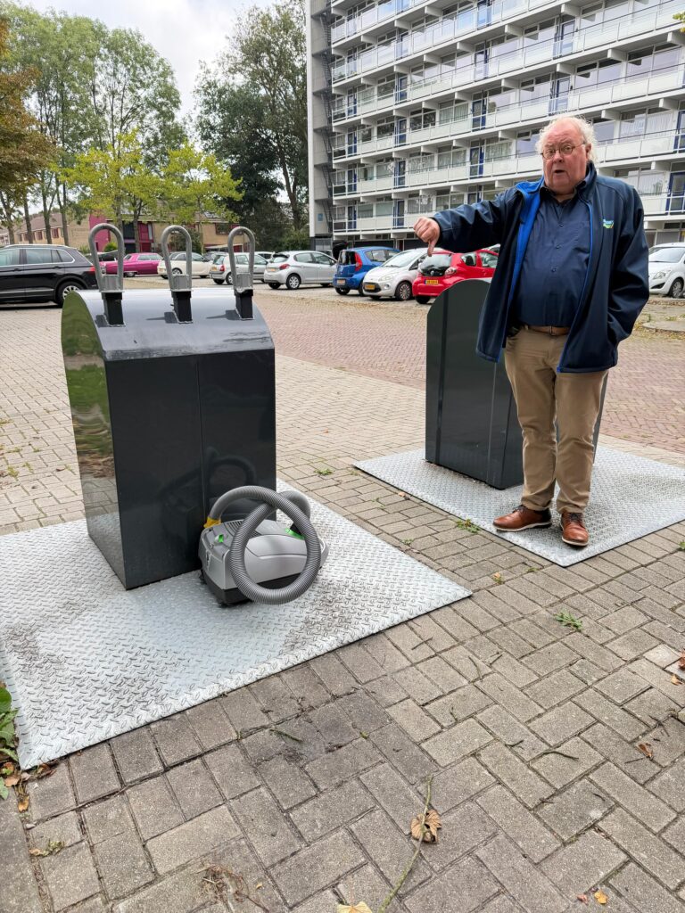 Age Hartsuiker wijst naar zwerfafval naast de container